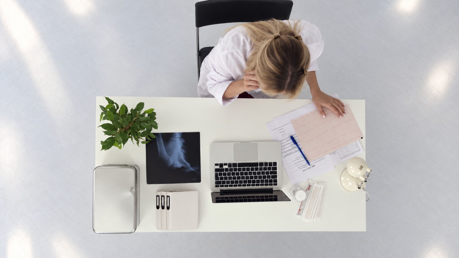 Overhead photograph of a woman reviewing clinical documents at a desk